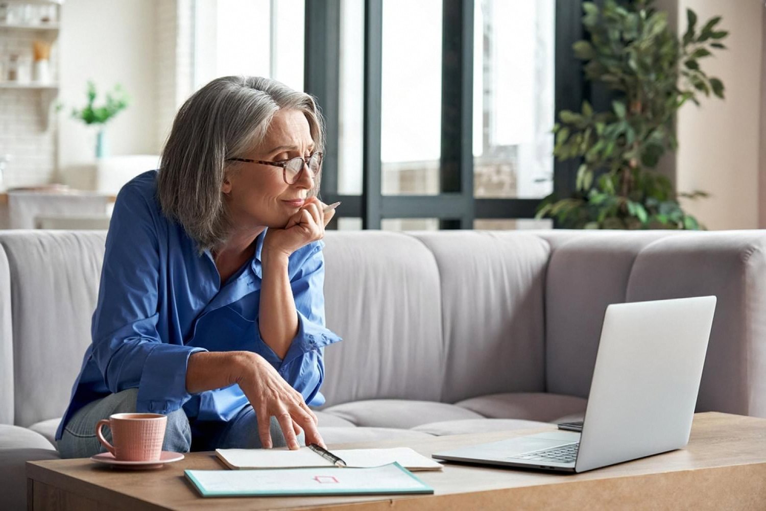 Woman comparing domain extensions and taking notes on a notepad at home