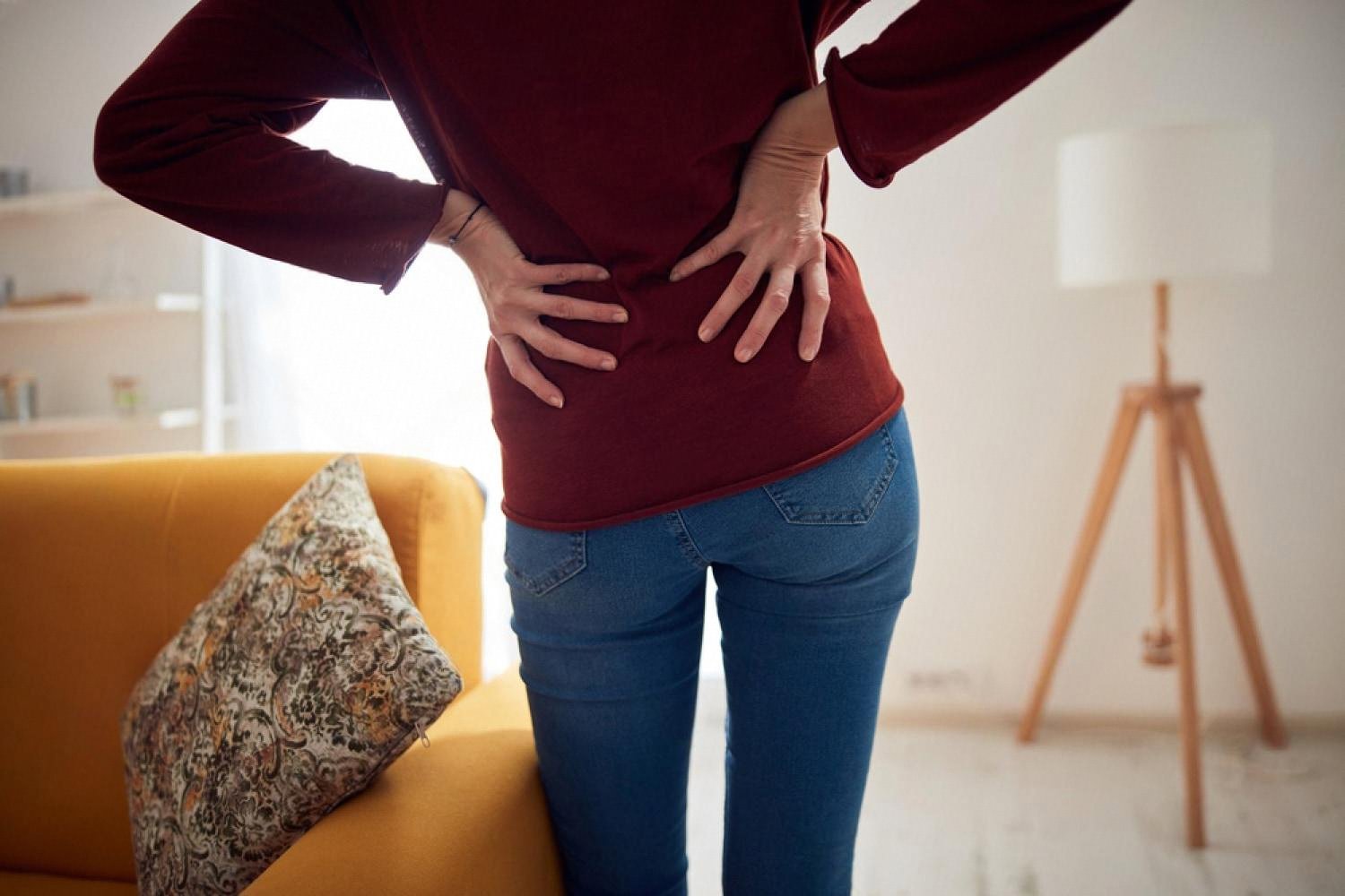 Patient holding lower back and abdomen showing typical hernia discomfort at home